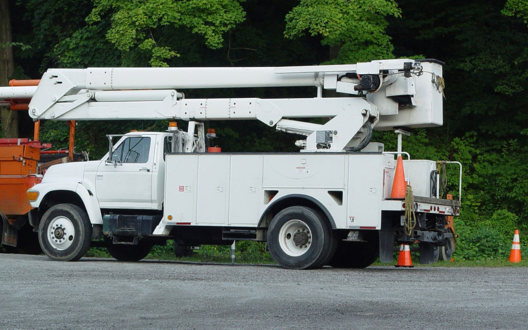 A white utility truck parked on a street, showcasing its cargo area and ladder rack